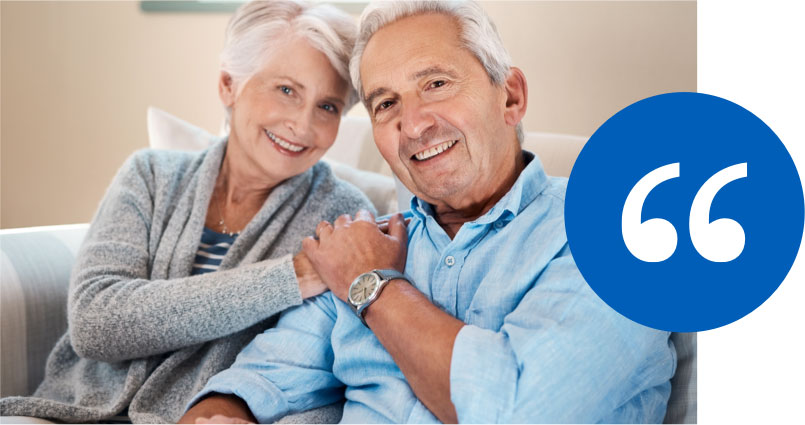 Smiling elderly couple sitting on a couch with a blue testimonial quotation icon.