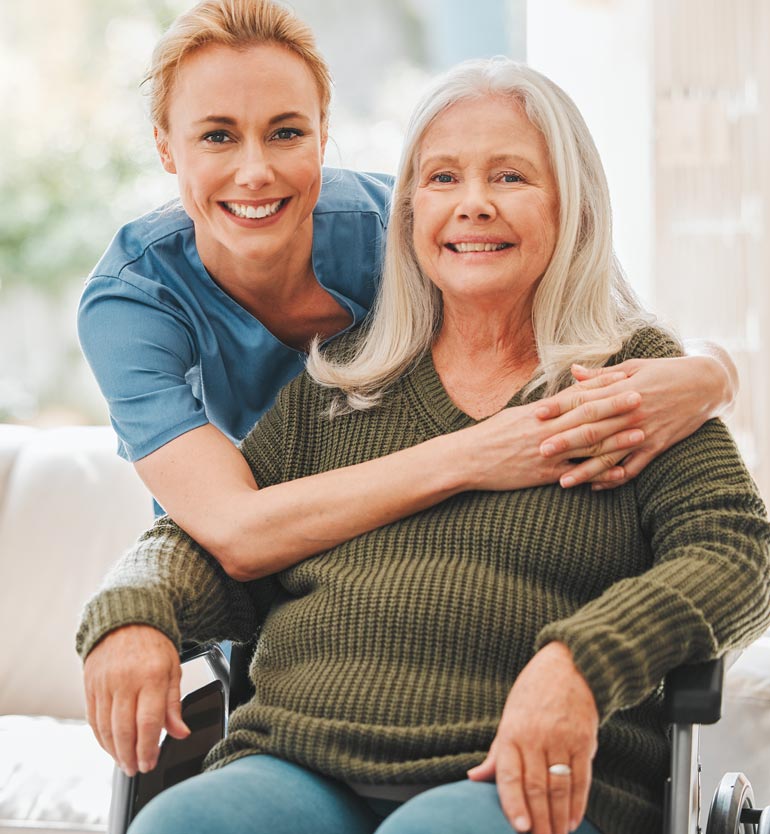 Smiling caregiver lovingly embraces an elderly woman in a wheelchair, fostering a warm connection