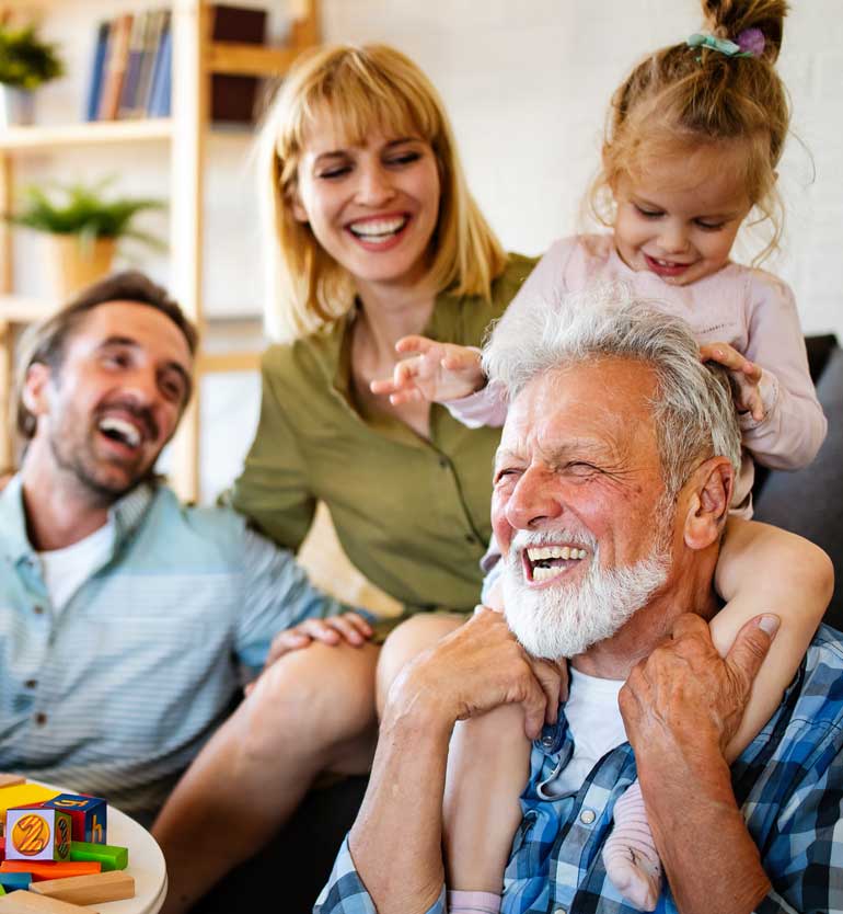 Senior man laughing with family, young girl on shoulders